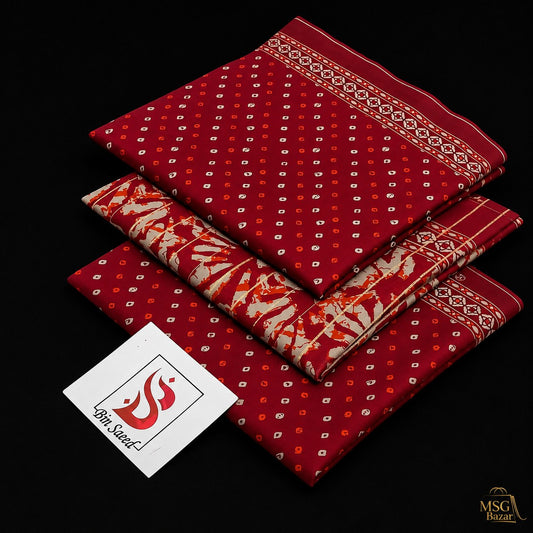 Three folded red patterned fabric pieces stacked on a black background, with a white tag reading '100% Silk' and a small 'MSG Bezar' logo in the bottom right corner.