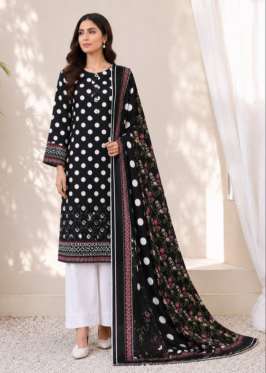 A woman models a black three-piece ethnic suit set featuring a kurta with white polka dots and border prints, white pants, and a matching dupatta with white polka dots and floral embroidery, set against a neutral indoor backdrop.