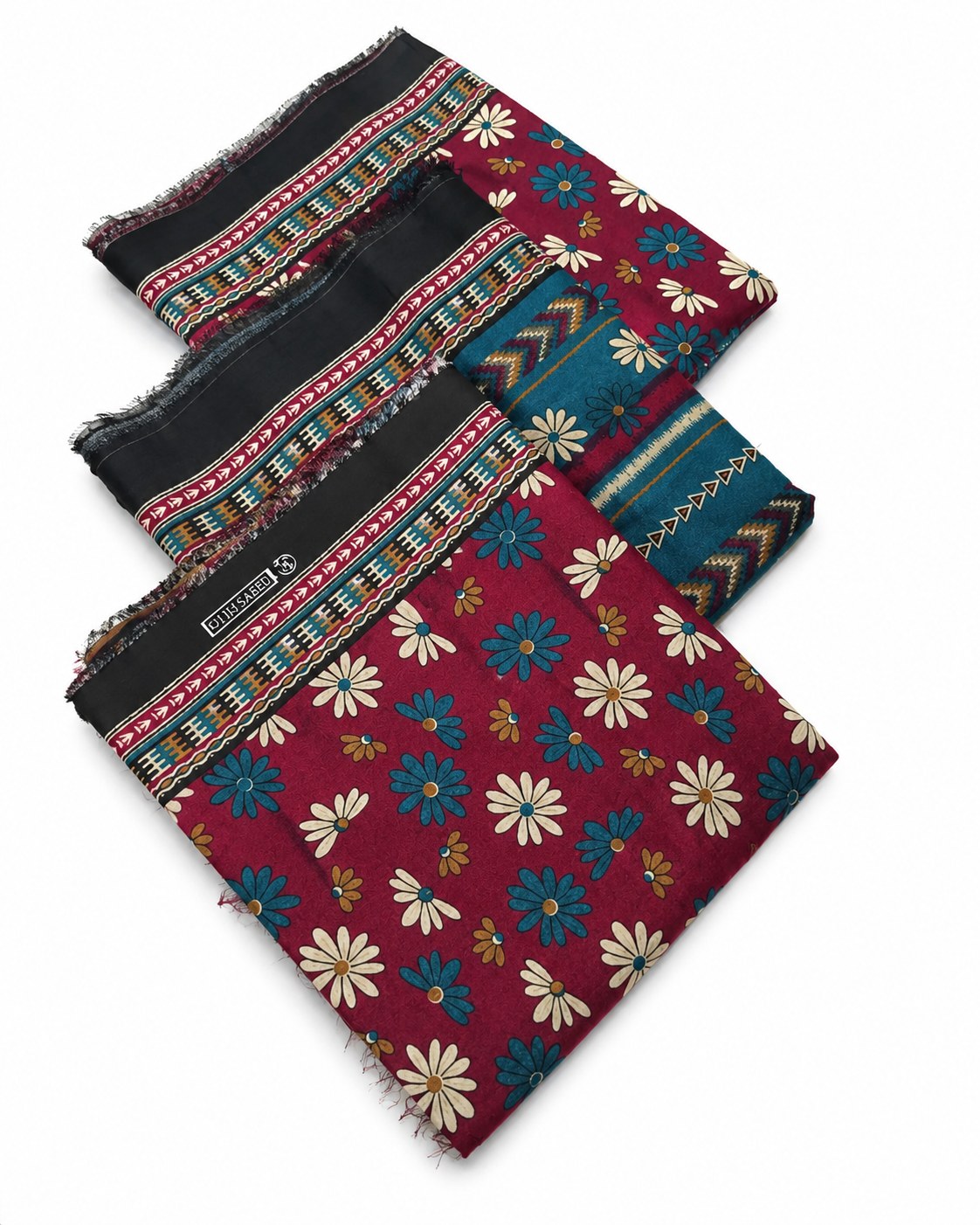 Three folded patterned scarves stacked diagonally on a white background. The top scarf is black with colorful geometric borders.