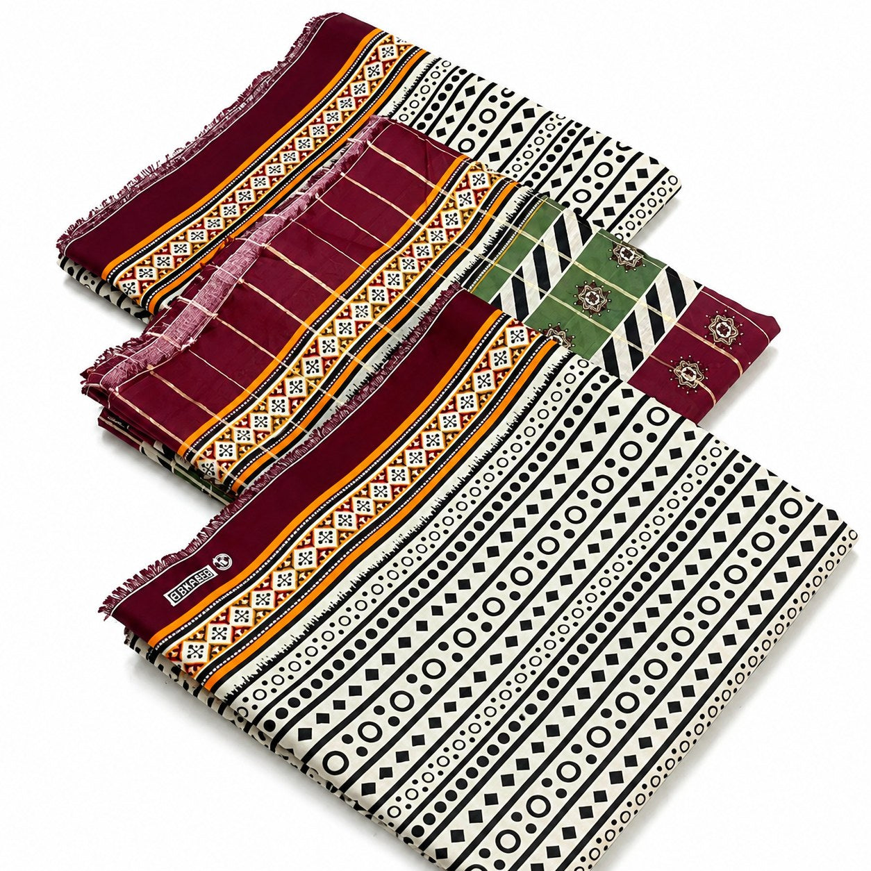 Four folded patterned textiles or scarves arranged diagonally on a white background. The fabrics feature geometric tribal-style prints in black, white, burgundy, green, and orange, with some showing fringed edges.