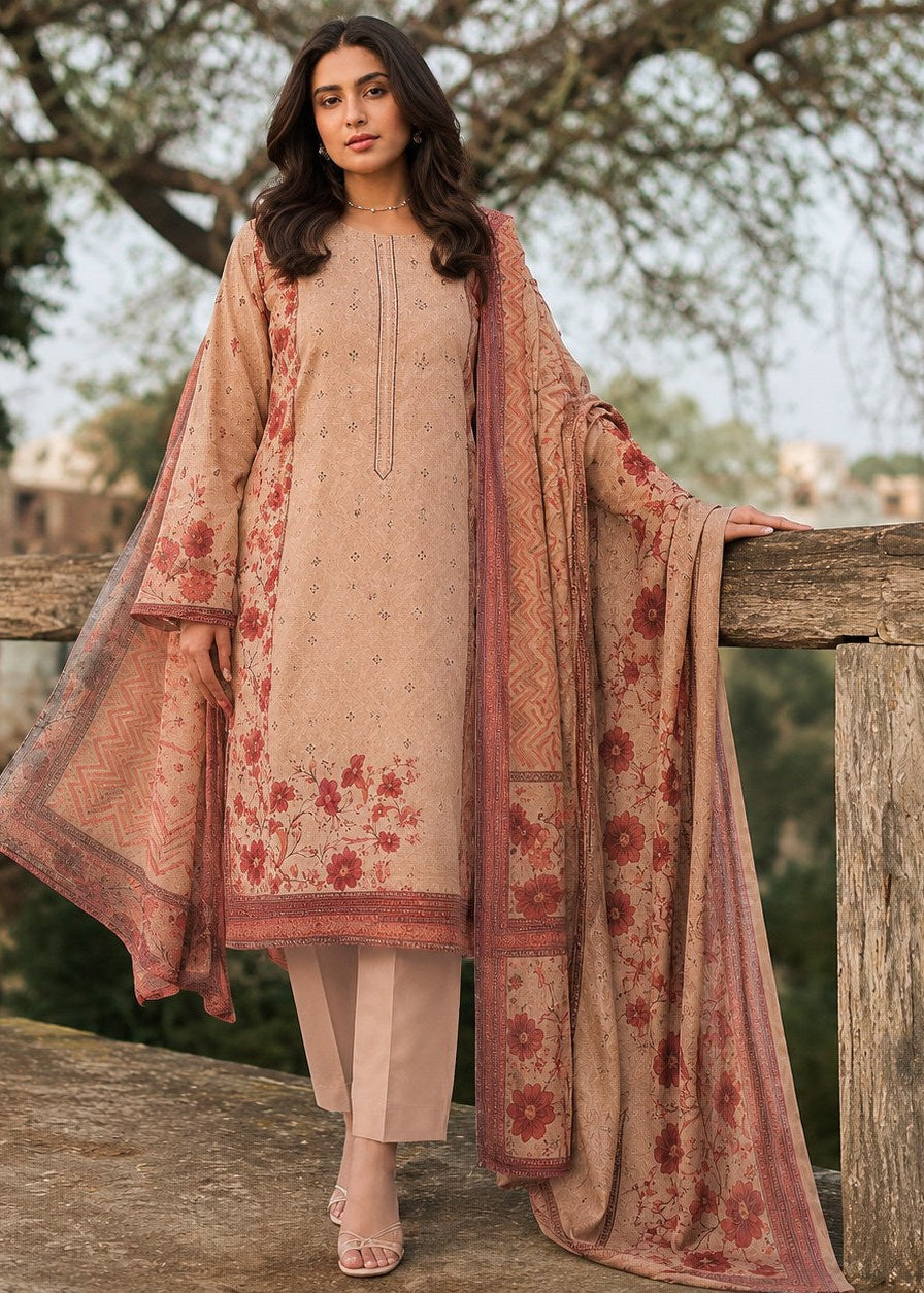 A woman models a traditional South Asian salwar kameez suit set in a warm beige/peach color with dusty red floral embroidery and a matching sheer dupatta, standing outdoors on a rustic wooden balcony.