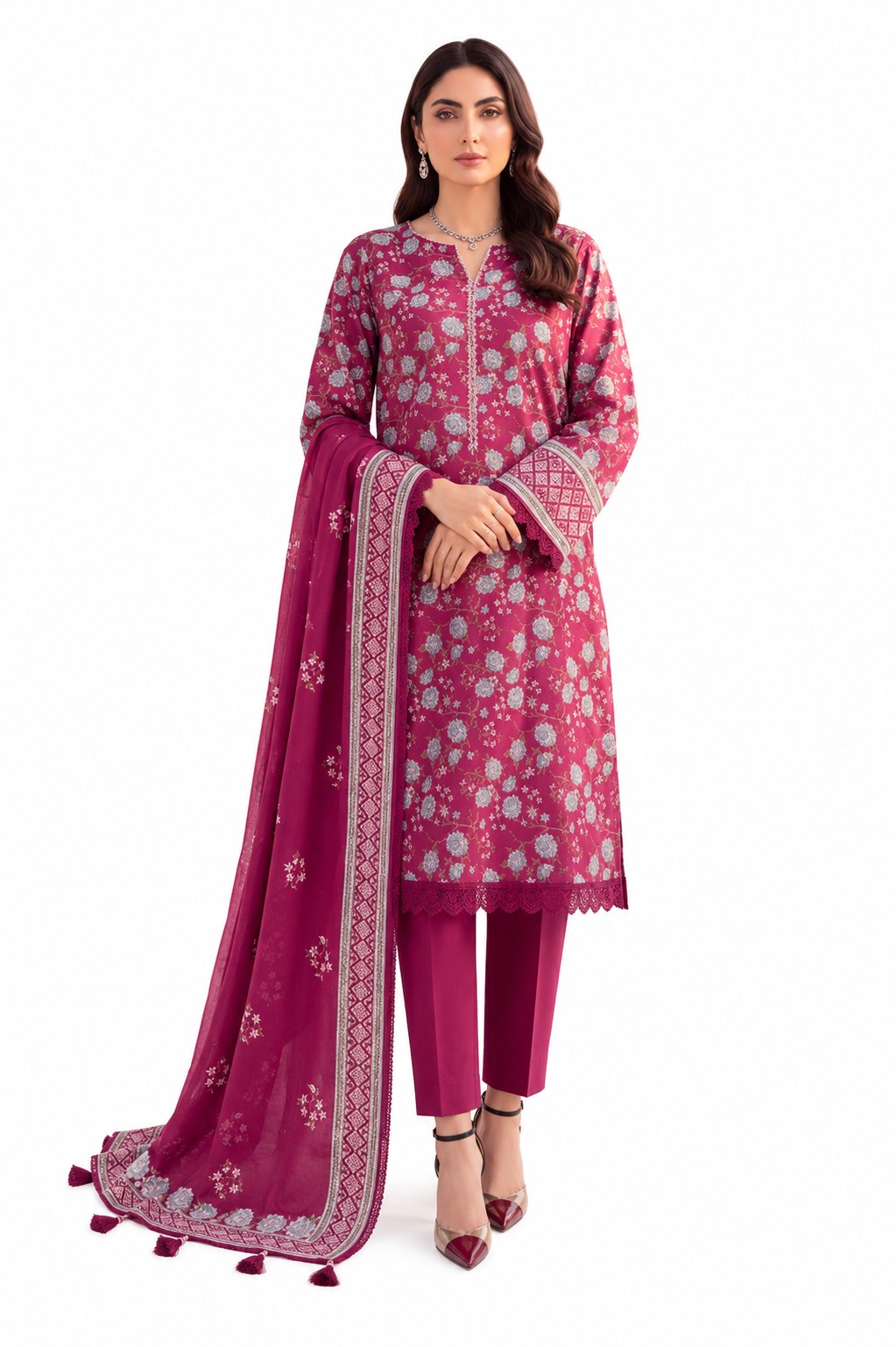 A woman models a three-piece salwar kameez suit set in magenta pink, featuring a floral printed tunic, matching trousers, and a coordinating dupatta with a white border and tassel details, set against a plain white background.