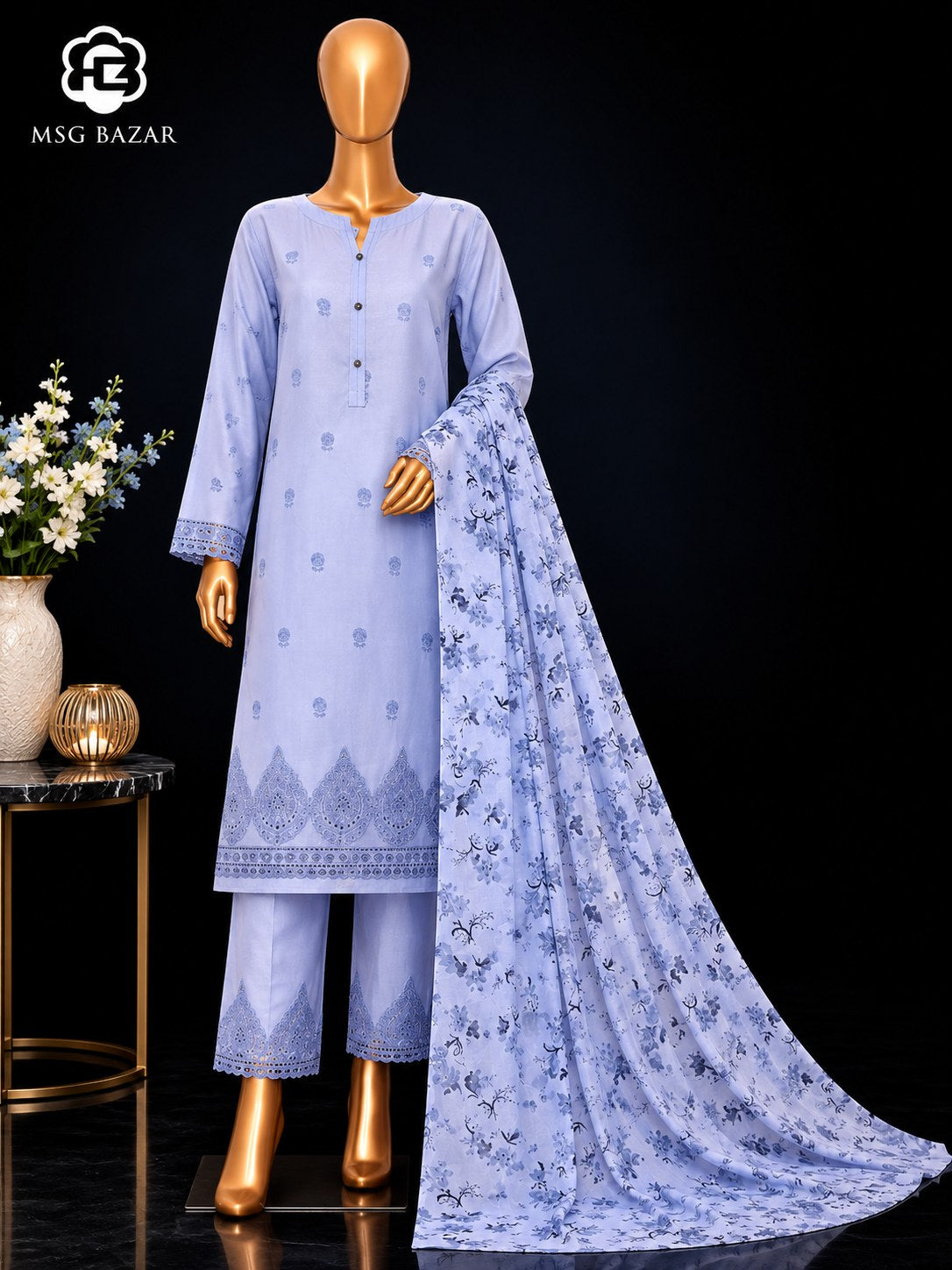 A light blue three-piece traditional outfit displayed on a gold mannequin against a black background, featuring a long kurta with embroidered details, matching pants, and a long printed dupatta. The MSG BAZAR logo is visible in the top left corner.
