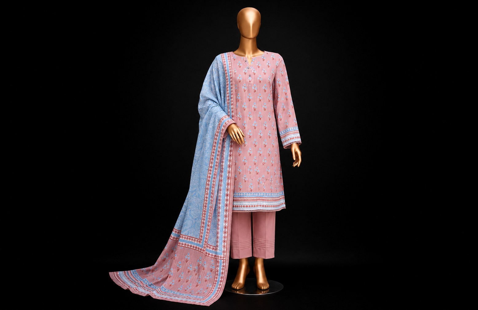 A three-piece women's traditional outfit displayed on a gold mannequin against a black background. The set includes a light pink kurta with small red floral motifs and border detailing, matching pink pants, and a light blue dupatta with a red border and floral pattern.