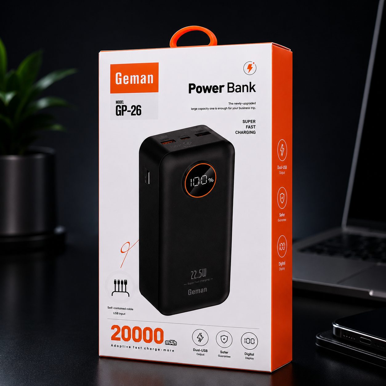 Geman Power Bank GP-26 retail packaging box shown on a dark tabletop with a blurred laptop and plant in the background. The box is white and orange with a large photo of the black power bank on the front.